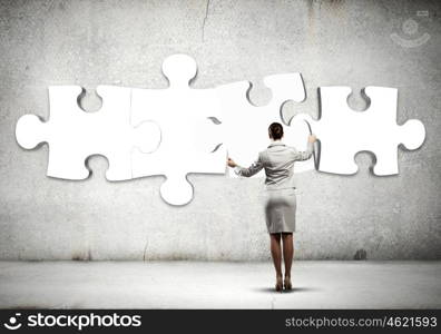 Logic thinking. Rear view of businesswoman connecting white puzzle