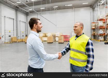 logistic business and cooperation concept - manual worker and businessman with clipboard shaking hands and making deal at warehouse. worker and businessman with clipboard at warehouse. worker and businessman with clipboard at warehouse