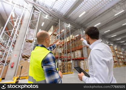 logistic business and people concept - businessman showing warehouse to worker. businessman showing warehouse to worker