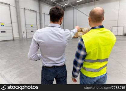 logistic business and people concept - businessman showing warehouse to worker. businessman showing warehouse to worker