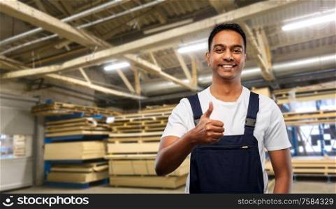 logistic business and people concept - happy smiling indian loader or worker showing thumbs up over warehouse background. happy indian worker showing thumbs up at warehouse