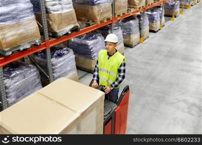 logistic business, shipment and loading concept - loader in helmet operating forklift at warehouse. loader operating forklift at warehouse