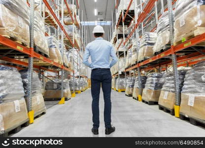 logistic business, shipment and people concept - businessman in helmet at warehouse. businessman in helmet at warehouse. businessman in helmet at warehouse