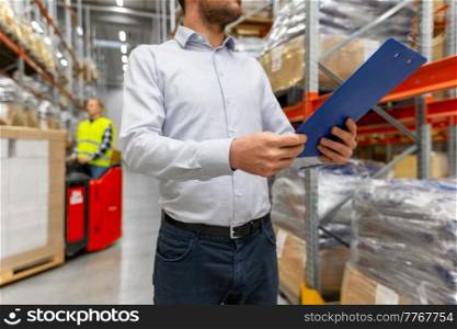 logistic business, shipment and people concept - close up of businessman with clipboard at warehouse. businessman with clipboard at warehouse