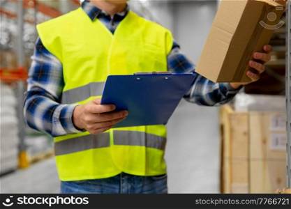 logistic business, shipment and people concept - close up of male worker or supervisor with box and clipboard in reflective safety vest at warehouse. worker with box and clipboard at warehouse
