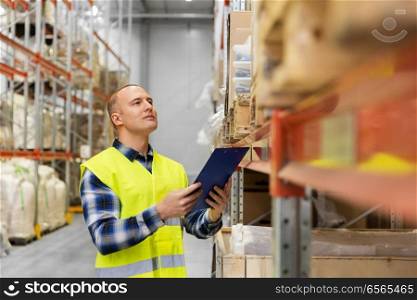 logistic business, shipment and people concept - male worker or supervisor with clipboard in reflective safety vest at warehouse. warehouse worker with clipboard in safety vest