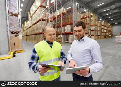 logistic business, shipment and people concept - warehouse worker and businessman with clipboard and tablet pc computer. worker and businessman with tablet pc at warehouse