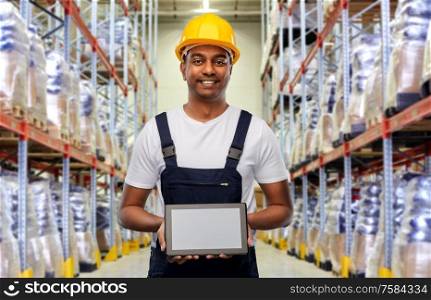 logistic business, technology and people concept - happy smiling indian loader or worker in helmet with tablet pc computer over warehouse background. happy indian worker with tablet pc at warehouse