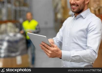 logistic business, technology and shipment concept - close up of happy businessman with tablet pc computer checking goods at warehouse. happy businessman with tablet pc at warehouse