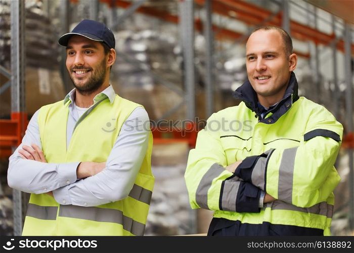 logistic, delivery, shipment, people and export concept - happy men or manual workers in reflective uniform at warehouse