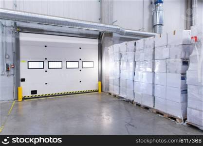 logistic, storage, shipment, industry and manufacturing concept - warehouse door or gate and cargo boxes