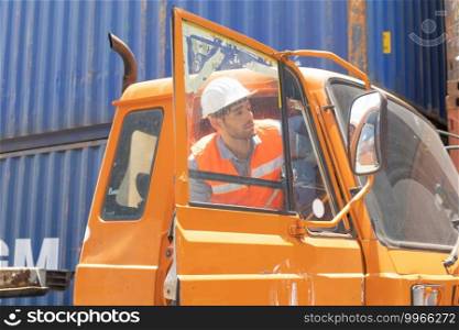 Logistic worker engineer man in truck car cabin working and talking to colleagues by walky talky in cargo container warehouse industry site in transportation concept. Business people lifestyle.