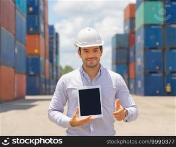 Logistic worker engineer man using a blank tablet, working in cargo container warehouse industry factory site in export, import, and transportation concept. Business people. Technology device.