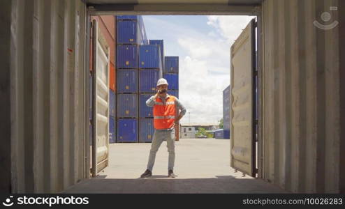 Logistic worker engineer man working in cargo container warehouse industry factory site in export, import, and transportation concept. Business people lifestyle. Distribution service.