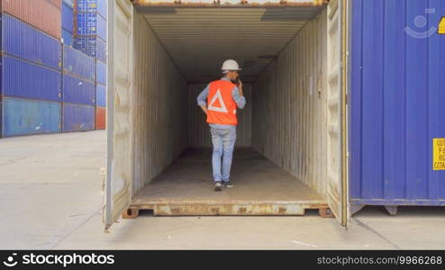 Logistic worker engineer man working in cargo container warehouse industry factory site in export, import, and transportation concept. Business people lifestyle. Distribution service.