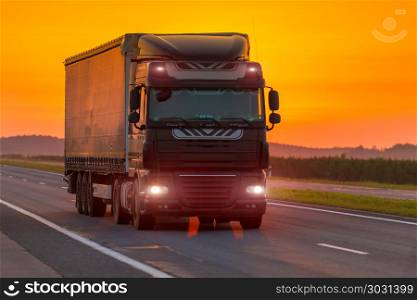 logistics truck on the highway at dawn, orange sky