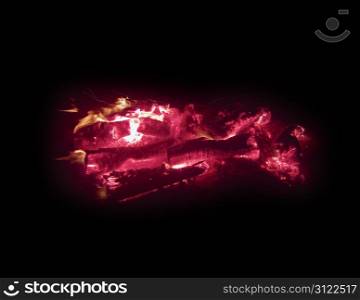 Logs burning with red hot embers in a camp fire pit on Cannon Beach.