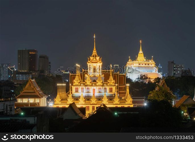 Loha Prasat Wat Ratchanatda and Golden Mountain pagoda, a buddhist temple or Wat Saket with skyscraper buildings in Bangkok Downtown, urban city at night, Thailand. Thai Landmark. Architecture.