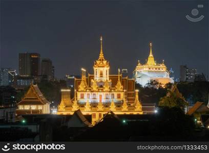 Loha Prasat Wat Ratchanatda and Golden Mountain pagoda, a buddhist temple or Wat Saket with skyscraper buildings in Bangkok Downtown, urban city at night, Thailand. Thai Landmark. Architecture.