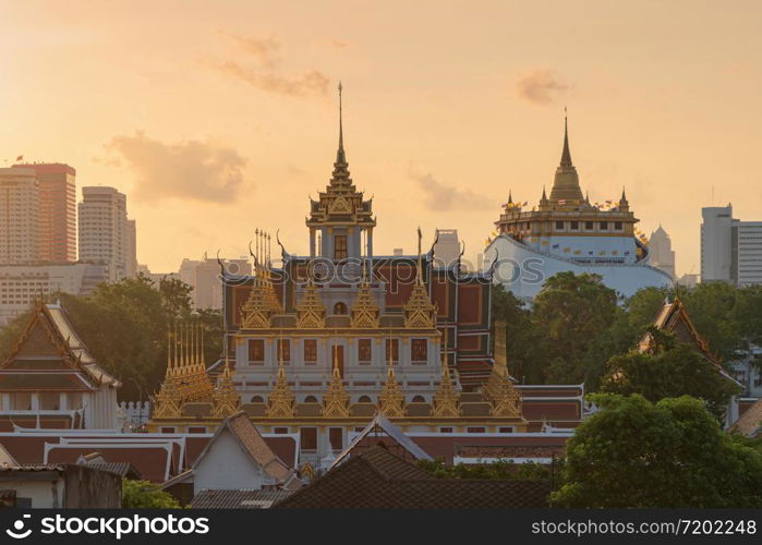 Loha Prasat Wat Ratchanatda and Golden Mountain pagoda, a buddhist temple or Wat Saket with skyscraper buildings in Bangkok Downtown, urban city at sunset, Thailand. Thai Landmark. Architecture.