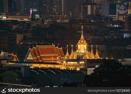 Loha Prasat, Wat Ratchanatda, and skyscraper buildings at night in Bangkok City, Thailand. Buddhist temples.