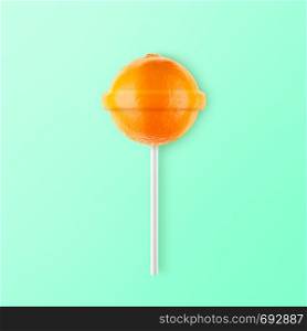 Lollipop orange isolated on mint background. Creative candy idea. Lollipop orange