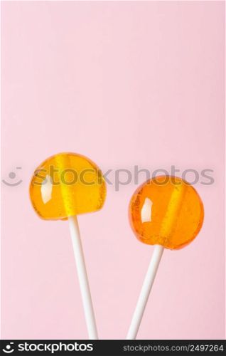 Lollipops on white plastic sticks on pink pastel background vertical with copy space