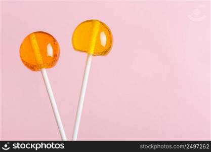 Lollipops on white plastic sticks on pink pastel background with copy space