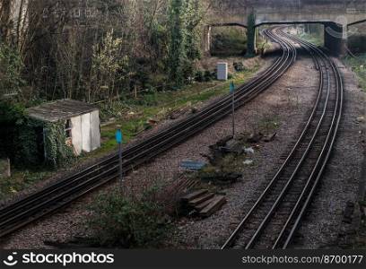 London, England - Mar 06, 2019   Two old railway tracks stretching into passing under the bridge. Perspective of routes and railroad train tracks in london, No focus, specifically.