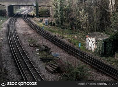 London, England - Mar 06, 2019   Two old railway tracks stretching into passing under the bridge. Perspective of routes and railroad train tracks in london, Selective focus.