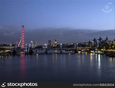 london eye with parliament and big ben behind river thames at night seen from waterloo bridge