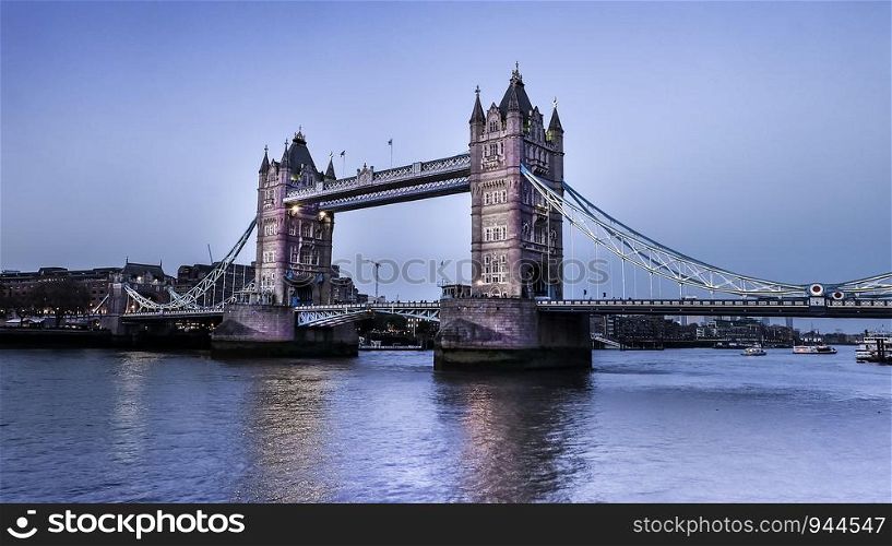 London, UK - Apr 20, 2019 : City views along the famous Tower Bridge in the evening with blue skies and reflections in Thames River.