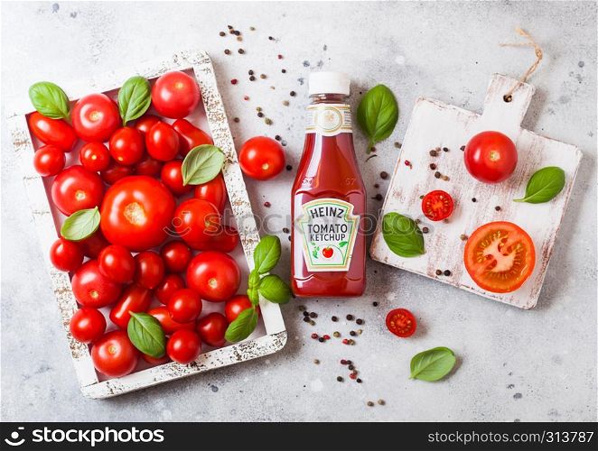 LONDON, UK - SEPTEMBER 13, 2018: Heinz ketchup with fresh raw tomatoes in box on stone background.
