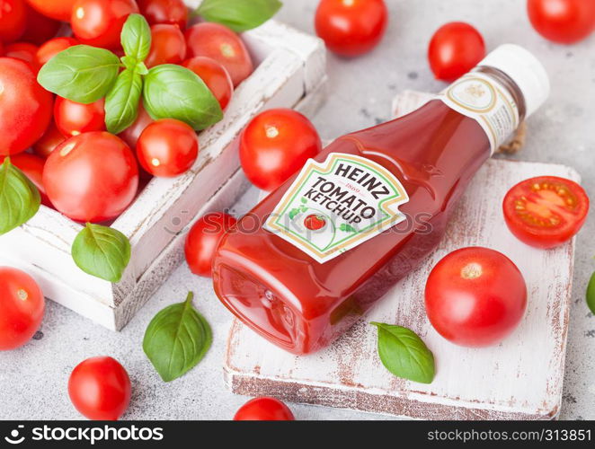 LONDON, UK - SEPTEMBER 13, 2018: Heinz ketchup with fresh raw tomatoes in box on wood board.