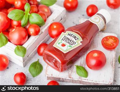 LONDON, UK - SEPTEMBER 13, 2018: Heinz ketchup with fresh raw tomatoes in box on wood board.