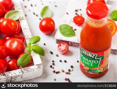 LONDON, UK - SEPTEMBER 13, 2018: Heinz tomato juice with fresh raw tomatoes in box on stone background.