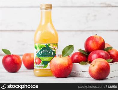 LONDON, UK - SEPTEMBER 13, 2018: Plastic bottle of fresh Copella Apple Juice with fresh apples in box on wood background.