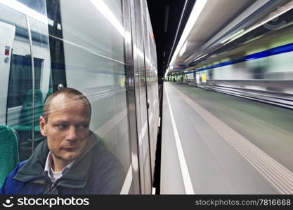 Lone man sitting in the subway on his way home passing a deserted station