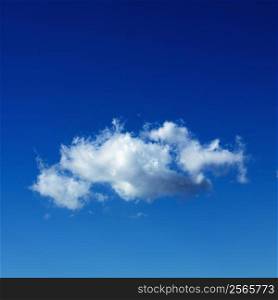 Lone puffy cumulus cloud in blue sky.