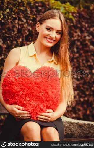 Loneliness valentine love romance dating concept. Cheering girl sitting on bench. Young lady holding heart. . Cheering girl sitting on bench.