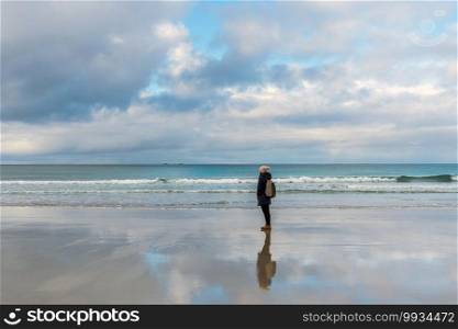 Lonely and depressed woman standing at the deserted sea beach,