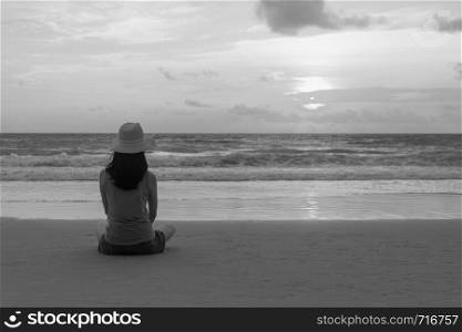 Lonely Asian woman thinking about problems and suffering at the beach during travel holidays vacation outdoors at ocean or nature sea at sunset time, Phuket, Thailand