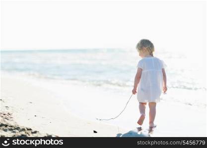 Lonely baby walking at seaside . rear view