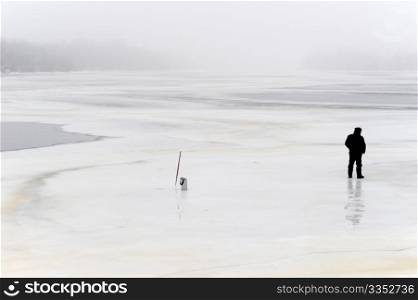 lonely fisherman on frozen river