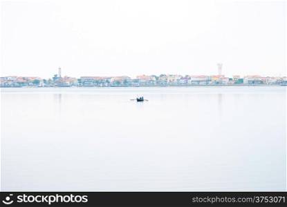 Lonely fishing boat with cityscape behind