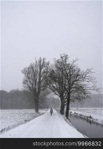 lonely male figure on snow covered country road in the netherlands near utrecht