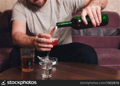 Lonely man drinking behind bottles of alcohol