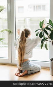 Lonely sad little girl sitting by the window.