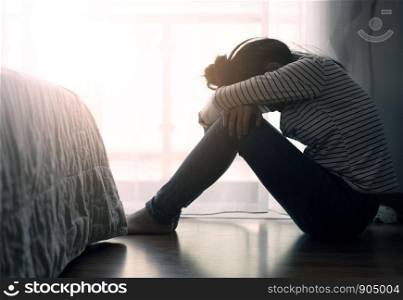 Lonely sad teenager student cry and hug her knees sitting in the dark corner ,Sad woman Unhappy and stressed student on the campus ,Family problems and education.major depressive disorder concept