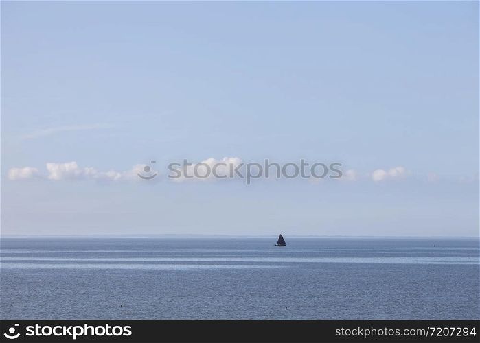 lonely sailing vessel on blue water on wadden sea in the dutch province of friesland
